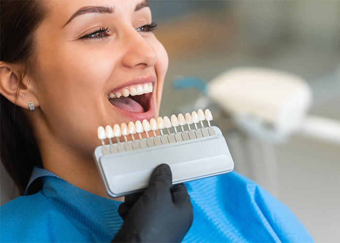 Smiling patient comparing tooth shades for a cosmetic dental treatment.
