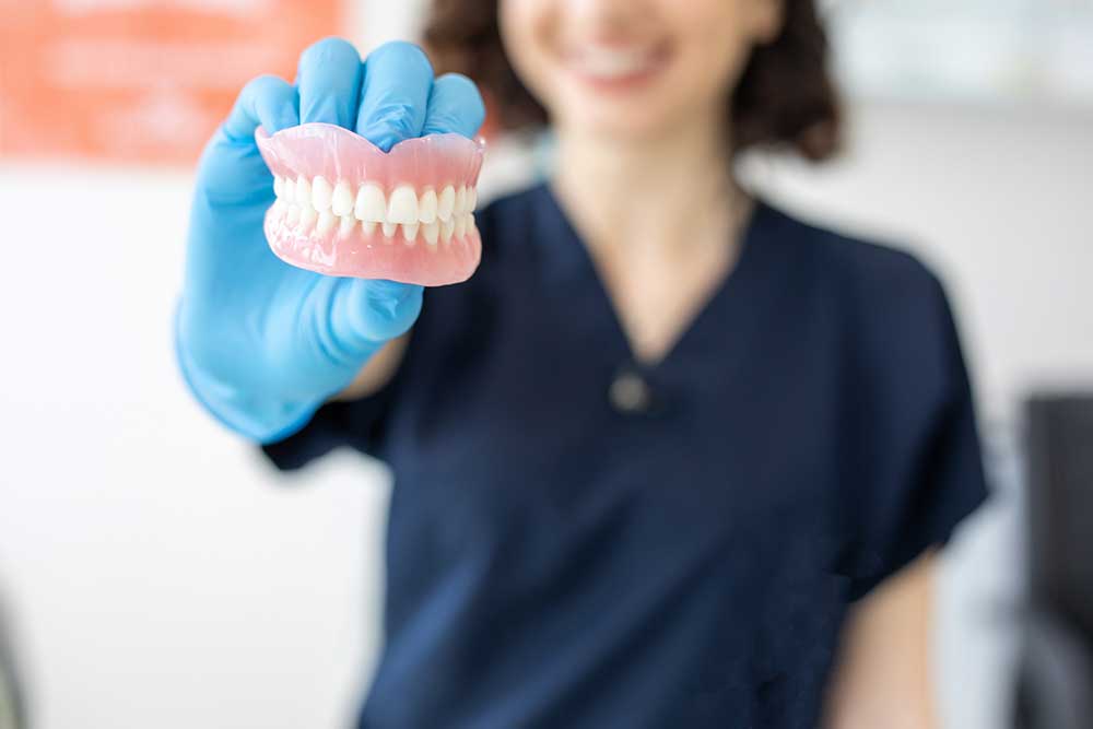 Dental professional holding a full set of removable dentures.